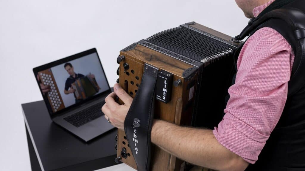 Harmonikaspieler lernt mit einem Laptop ein Harmonika-Stück