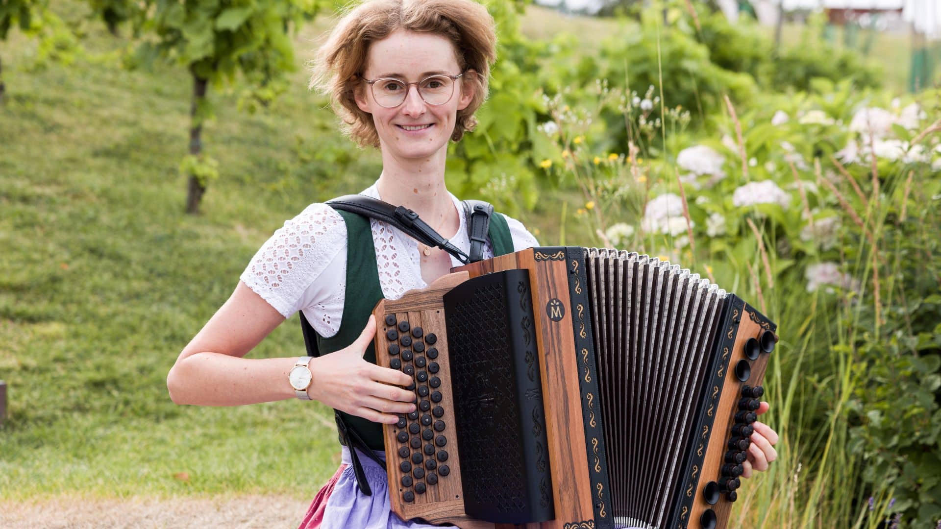 Celia schaut freundlich in die Kamera weil sie an Harmonika Repertoire pflegen denkt