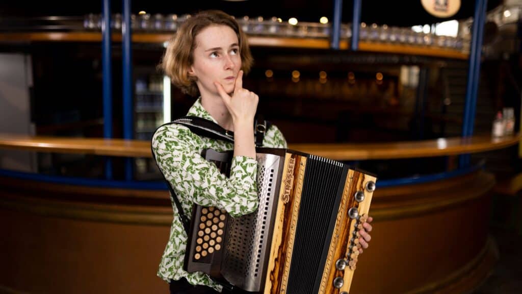 Celia schaut grübelnd und fragt sich warum Harmonikalernen ohne Harmonika üben nicht geht