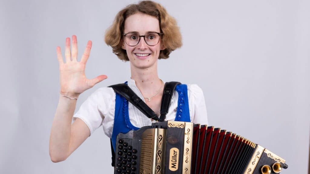 Celia  zeigt  fünf  Finger  als  Symbol  für  fünf  wertvolle  Erkenntnisse,  die  dein  Harmonikaspiel  verbessern.