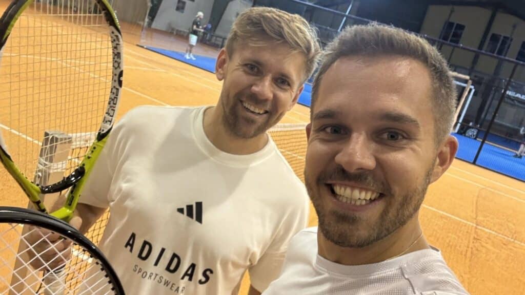 Richi  und  Jürgen  machen  ein  Selfie  mit  Tennisschlägern  auf  dem  Platz  zur  Verdeutlichung  der  Parallelen  zum  Harmonikaspielen