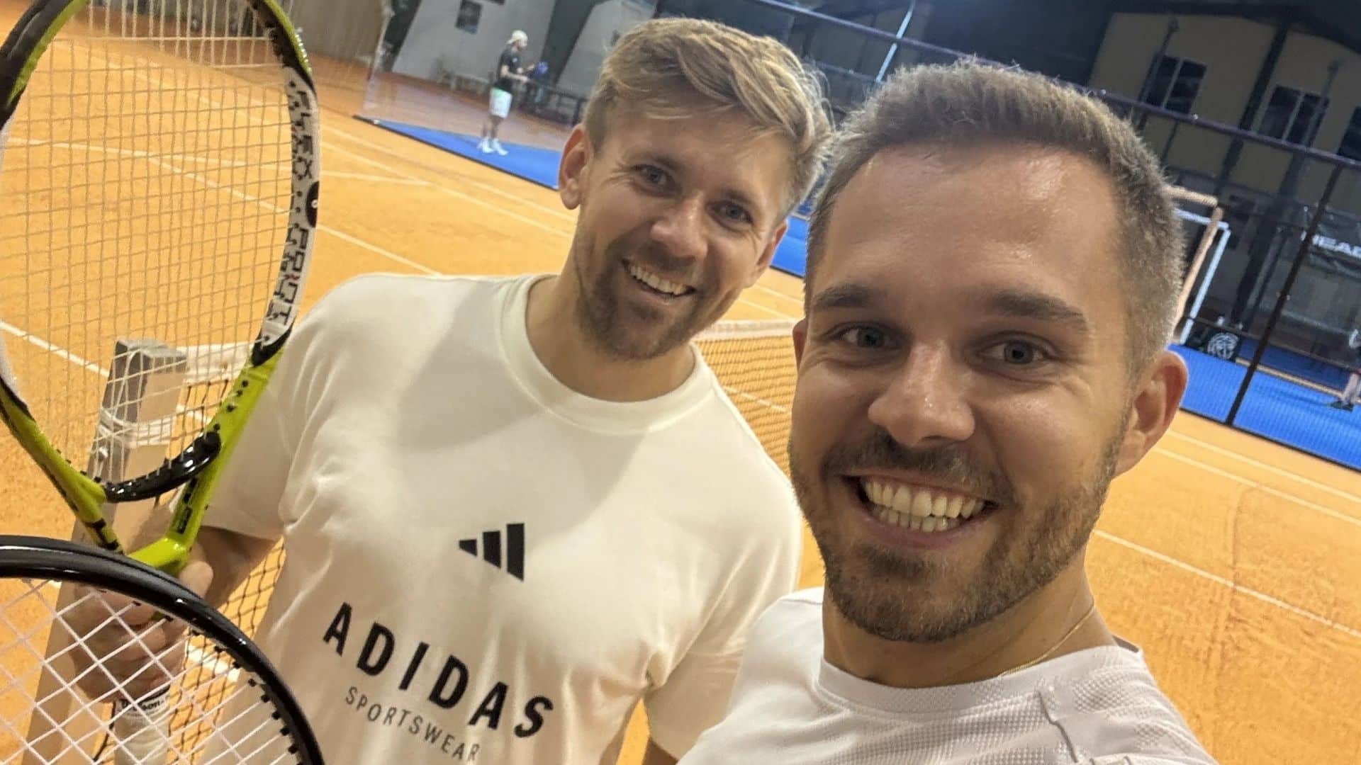 Richi und Jürgen machen ein Selfie mit Tennisschlägern auf dem Platz zur Verdeutlichung der Parallelen zum Harmonikaspielen